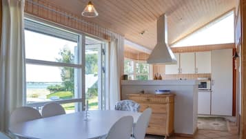 Een moderne keuken met houten kastjes, een eethoek met tafel en stoelen, en uitzicht op de omgeving.