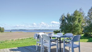 Una terraza con mesa y sillas que da a un lago, rodeada de vegetación.