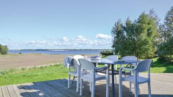 Een terras met een tafel en stoelen met uitzicht op een meer, omgeven door groen.