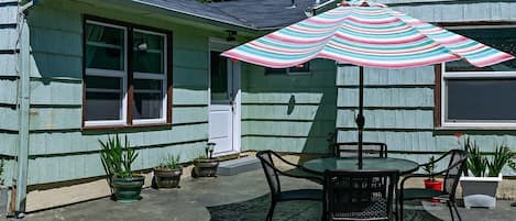 Une terrasse avec une table et des chaises, un parasol et des plantes en pot.