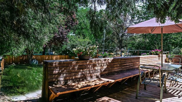 An outdoor patio with a wooden bench, a table, and an umbrella.