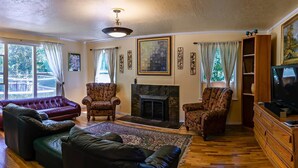 A living room with a fireplace, leather sofas, patterned armchairs, and a television.