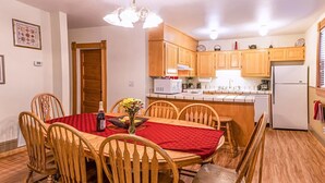 A dining area with a wooden table and chairs, a red tablecloth, and a vase with flowers. - Oak Sherwin House Near OSF (Ashland)