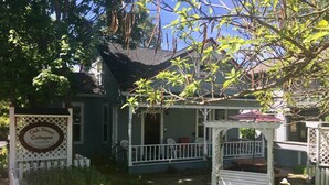 A cottage with a porch, a sign reading "Oak Street Cottages," and a welcome sign for pets. - Oak Sherwin House Near OSF (Ashland)