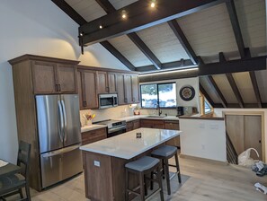 A modern kitchen with wooden cabinets, stainless steel appliances, and a large island with bar stools.