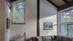 A living room with a large window, a sofa, a lamp, and framed pictures on the wall.