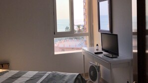 Una camera da letto con un letto, una scrivania con un computer e una finestra vista edifici e mare.