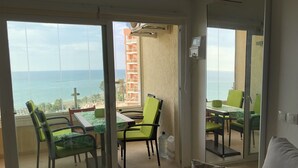 Un balcone con vista sul mare, arredato con poltrone verdi e un tavolo.