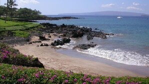 A beach with rocky shoreline, clear blue water, and distant mountains. - Beachfront  / Corner  / Renovated / 2nd floor condo unit: F-204 (Wailea-Makena)