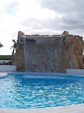 Una piscina amb una cascada artificial de pedra.
