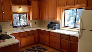 A kitchen with wooden cabinets, a microwave, a sink, and a refrigerator.
