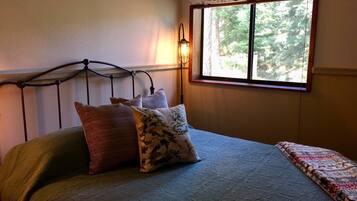 A bed with a metal headboard, two pillows, and a patterned bedspread.