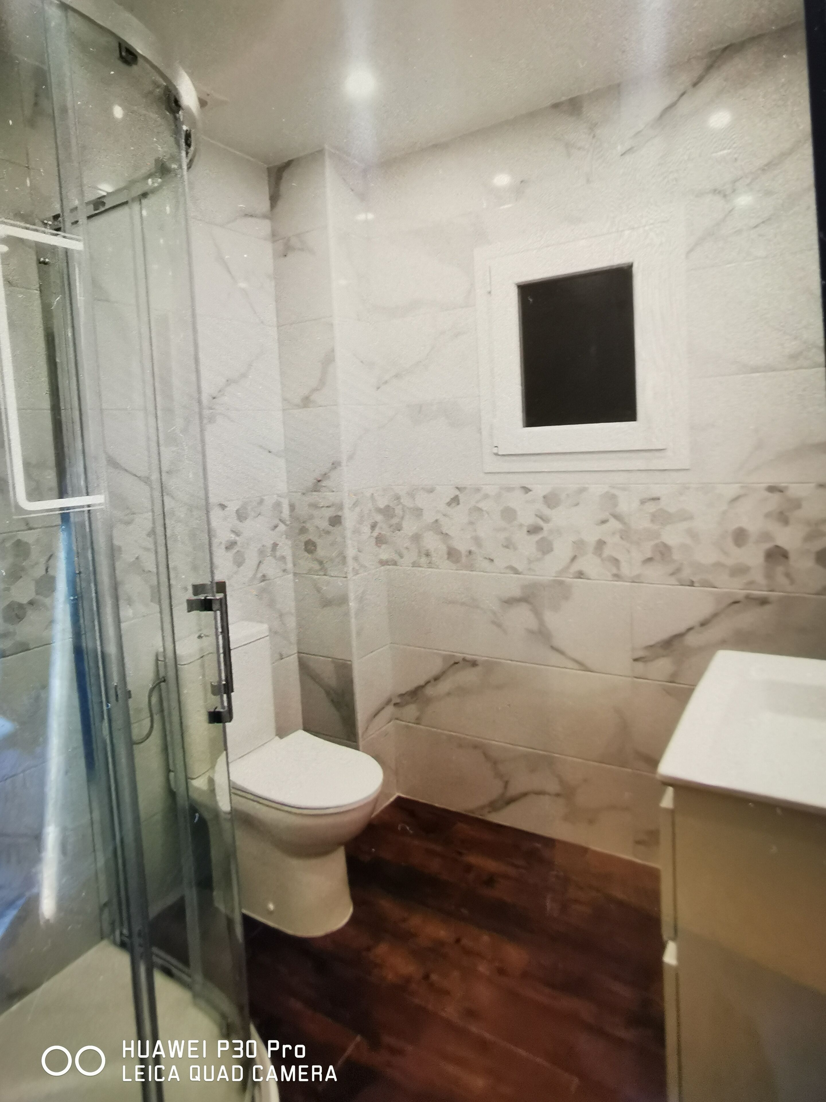Un baño con ducha de vidrio, inodoro y lavamanos.