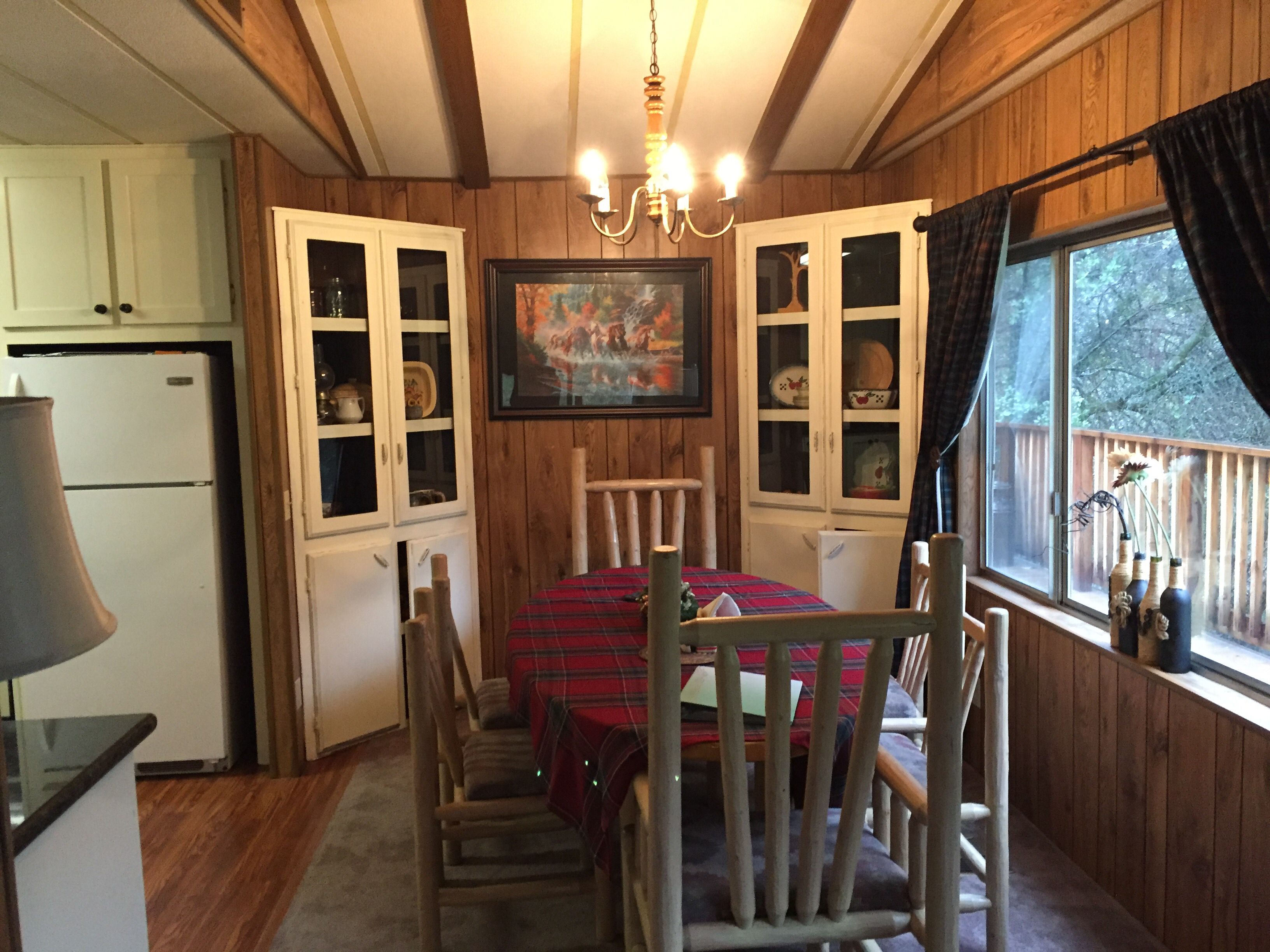 A cozy dining area with a wooden table and chairs, surrounded by wooden walls and cabinets.