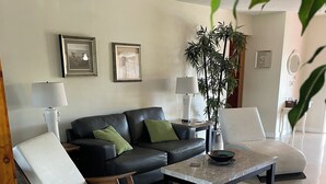 A living room with a black leather sofa, a white rocking chair, a coffee table, and a potted plant. - MINS from Everything -Private House 3/2- Pet Free/Smoke Free (Pembroke Pines)