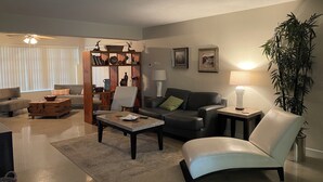 A living room with a sofa, armchair, coffee table, and a bookshelf. - MINS from Everything -Private House 3/2- Pet Free/Smoke Free (Pembroke Pines)