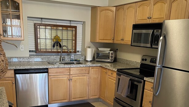 A kitchen with wooden cabinets, a stainless steel refrigerator, a microwave, a toaster, and a dishwasher. - MINS from Everything -Private House 3/2- Pet Free/Smoke Free (Pembroke Pines)