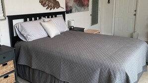 A bedroom with a bed, a nightstand, a wall-mounted air conditioner, and a door. - MINS from Everything -Private House 3/2- Pet Free/Smoke Free (Pembroke Pines)