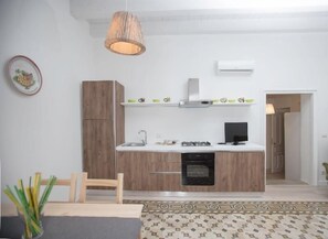 Una cocina moderna con armarios de madera, estufa integrada y una lámpara colgante.