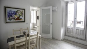 A room with a dining table, chairs, a framed picture, a door, and a window with a view. - Residence Ventimiglia (Gangi)