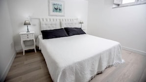 A bedroom with a white bed, two bedside tables with lamps, a white headboard, and a framed picture on the wall. - Residence Ventimiglia (Gangi)