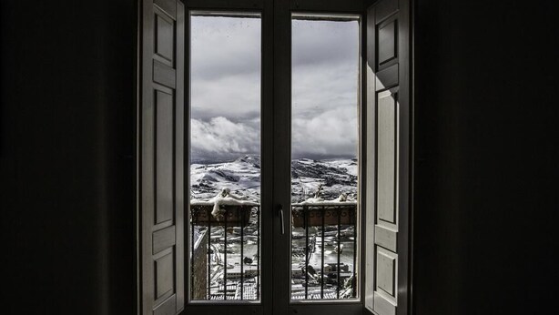 A room with a large window revealing a snowy outdoor scene. - Residence Ventimiglia (Gangi)