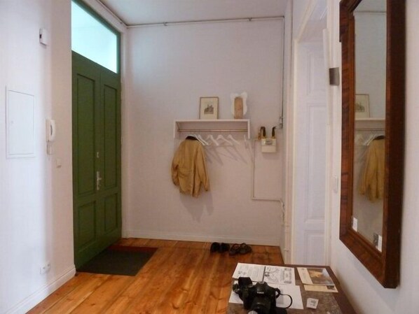 A hallway with wooden flooring, a green door, a coat rack with a jacket, and a mirror on the wall. - Wroclaw Charming Apartment 110m², 3 rooms, 2 bathrooms incl. WC, sleeps 6 (Wroclaw)