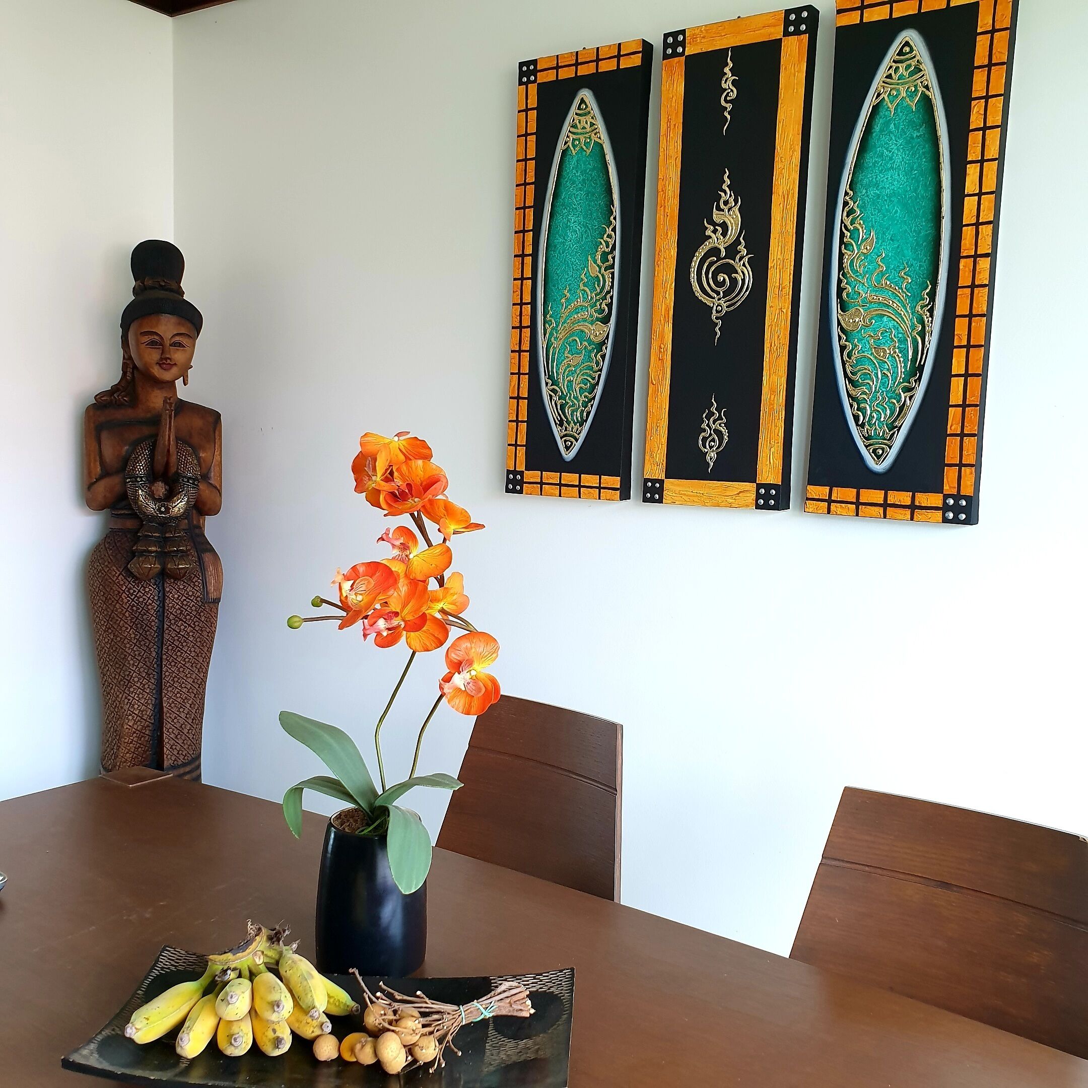 A dining table with a vase of flowers and a fruit arrangement.