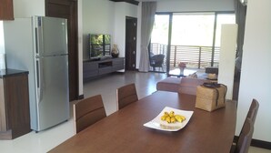 A modern kitchen with a built-in refrigerator, a dining area with a wooden table and chairs, and a living area with a sofa and a TV. - Splendid PENTHOUSE 120m² seaside, fitness room, panoramic view 4/5pers. (BO PHUT)