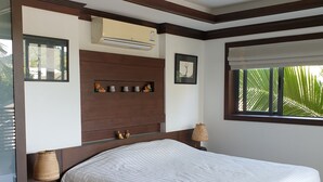 A bedroom with a large bed, wooden headboard, wall-mounted air conditioning, a window with a view of palm trees, and a small shelf with decorative items. - Splendid PENTHOUSE 120m² seaside, fitness room, panoramic view 4/5pers. (BO PHUT)