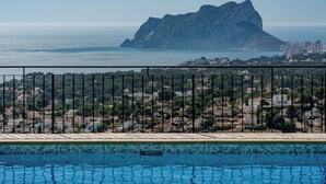 Une piscine offrant une vue sur un paysage montagneux et une ville lointaine.