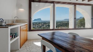 Une cuisine dotée d’une grande fenêtre, d’une table à manger et offrant une vue sur le paysage urbain.