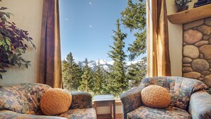 A cozy seating area with patterned upholstery and a view of snow-capped mountains through large windows. - Spectacular Views, Hiking & Skiing, Spacious Cozy Luxury, Hot tub, Fireplace (Breckenridge)