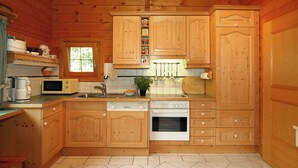 A wooden cabin-style kitchen with a dishwasher, oven, microwave, and a window. - Quietly located, luxurious 4-stars-country house with private pool (Schiefling am See)