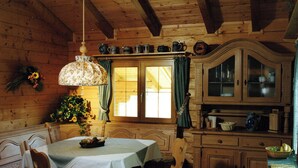 A wooden interior with a dining table, chairs, a cabinet, and a hanging light fixture. - Quietly located, luxurious 4-stars-country house with private pool (Schiefling am See)