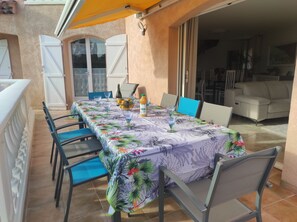 Enjoy meals al fresco in this charming outdoor dining area with a long table set for a meal.