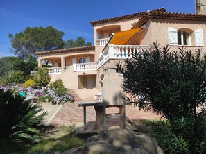 Relax on the villa's spacious balcony with a view of the surrounding courtyard, complete with a bench and lush greenery.