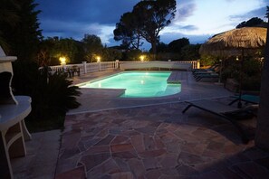 Relax by the pool surrounded by lush greenery and comfortable lounge chairs.