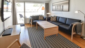 A modern living room with a sofa, a coffee table, a TV, and a large window. - Awesome apartment in Faaborg with WiFi (Faaborg)