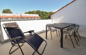Relax on the outdoor patio with a table and four chairs, surrounded by a charming urban view.