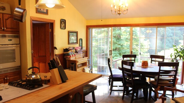 A kitchen with a stove, sink, and a dining area with chairs and a table. - Grandma's House: Riverfront, Gorgeous View, Beach/Swimming/Canoeing Dog Friendly (Monte Rio)