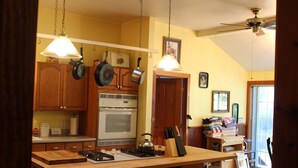 A kitchen with wooden cabinets, a stove, and hanging pots. - Grandma's House: Riverfront, Gorgeous View, Beach/Swimming/Canoeing Dog Friendly (Monte Rio)