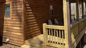 A wooden cabin with a porch and a covered deck area.