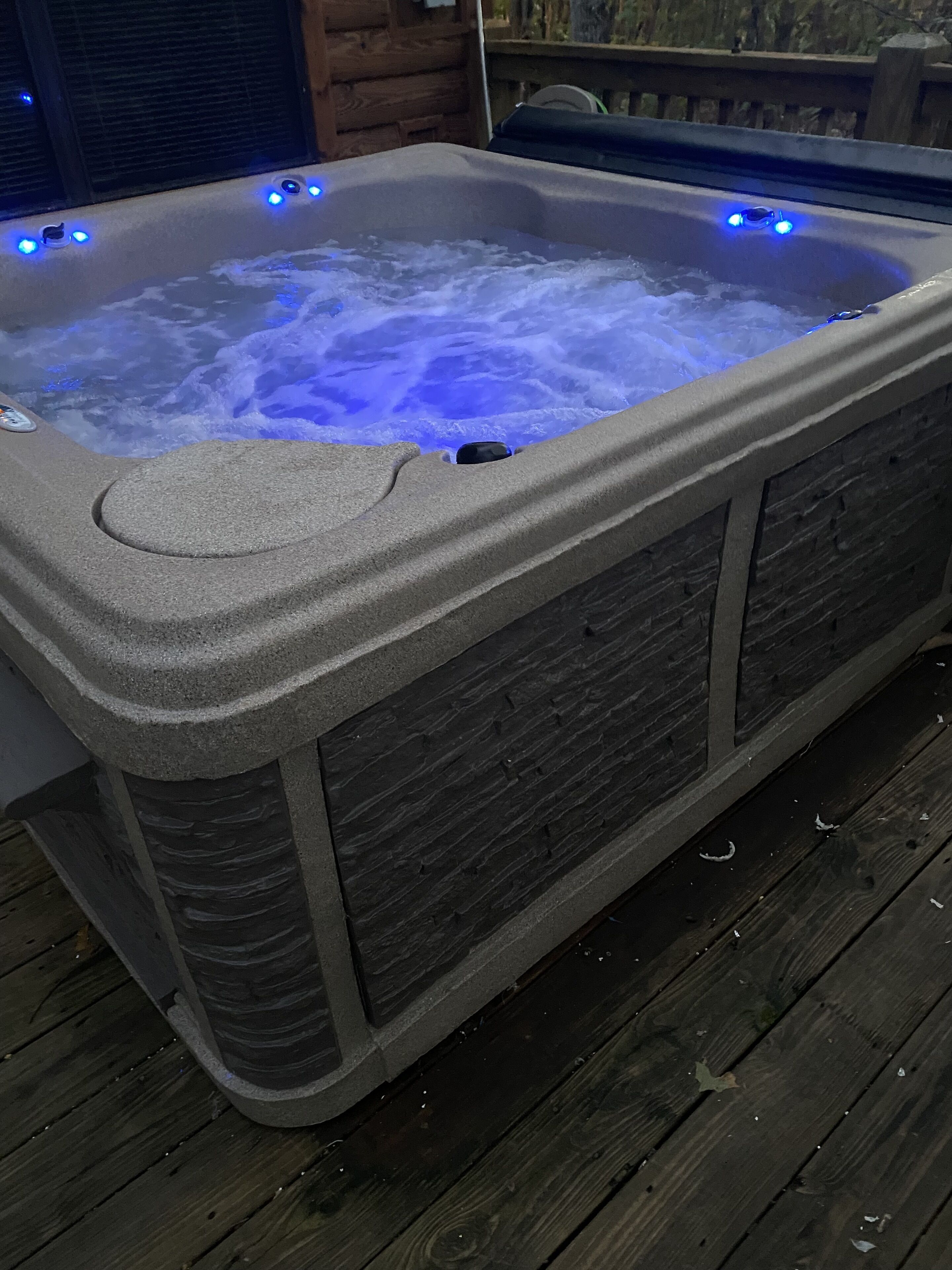 A hot tub with a stone exterior and blue LED lights.