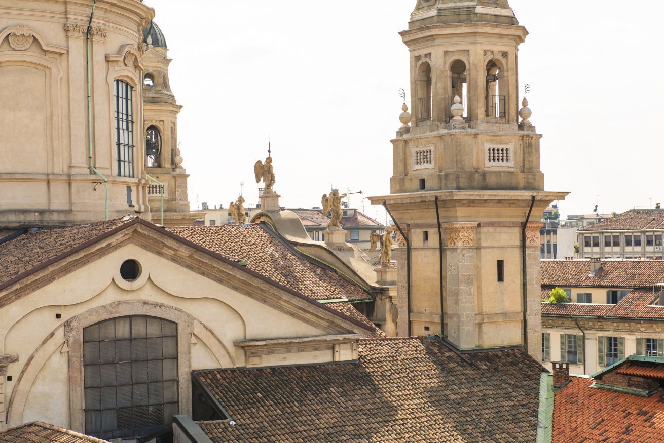 A historic building with a bell tower, arched windows, and statues.