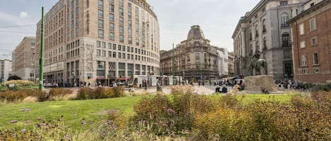 Un edificio storico con una cupola centrale, circondato da una piazza con una statua e una fontana.