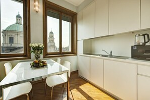 Una cocina moderna con una mesa de comedor, sillas blancas, una cafetera y vistas a un edificio histórico.