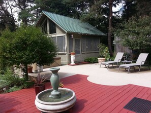 A wooden deck with a fountain, potted plants, and outdoor seating. - Unique Artisan home, near water, beach ,biking & hiking trails,3 bedroom,Hot tub (Two Rivers)
