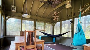 Eine rustikale Holzhütte mit Esstisch, Stühlen und einer Hängematte.