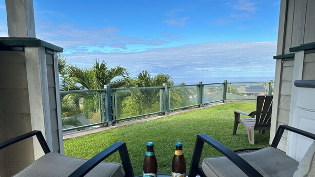 Un patio con due bottiglie di birra, un tavolo in vetro e vista sull'oceano.